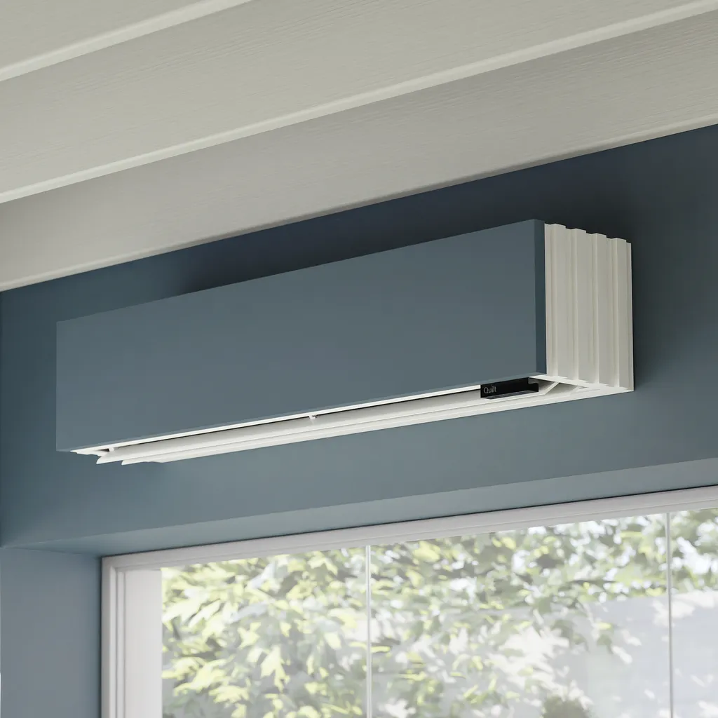 Photo of a gray Quilt heat pump installed on wall above a window